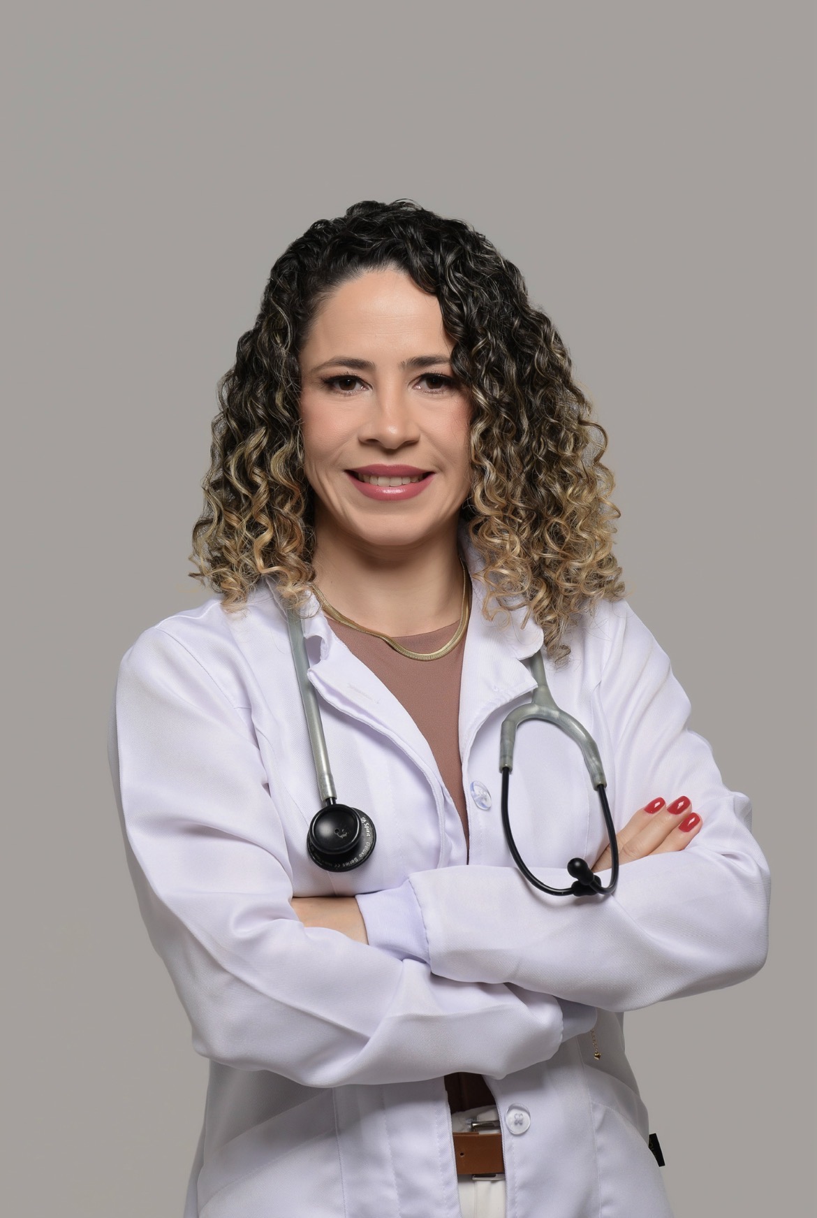 Elisângela Lima, fisioterapeuta, de braços cruzados com jaleco branco e estetoscópio
